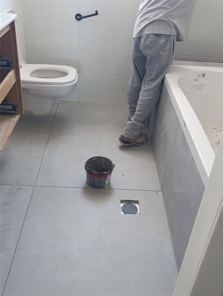 התקנת הכלים: אסלה תלויה ואמבטיה בחיפוי אפור